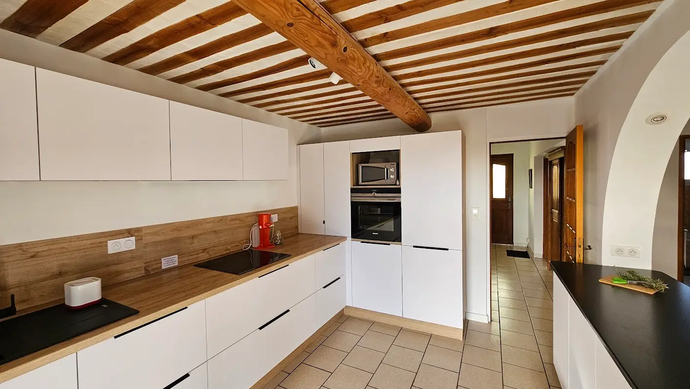 The white kitchen with a wooden worktop and built-in oven and microwave