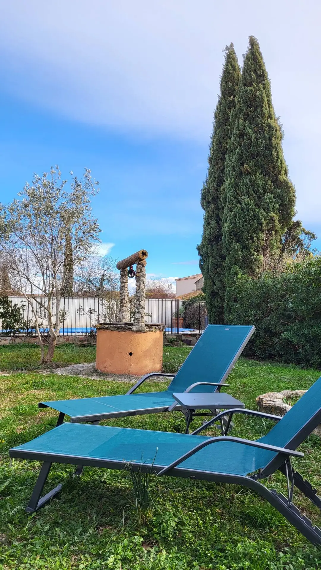 Der alte Steinbrunnen und eine Sonnenliege im Garten