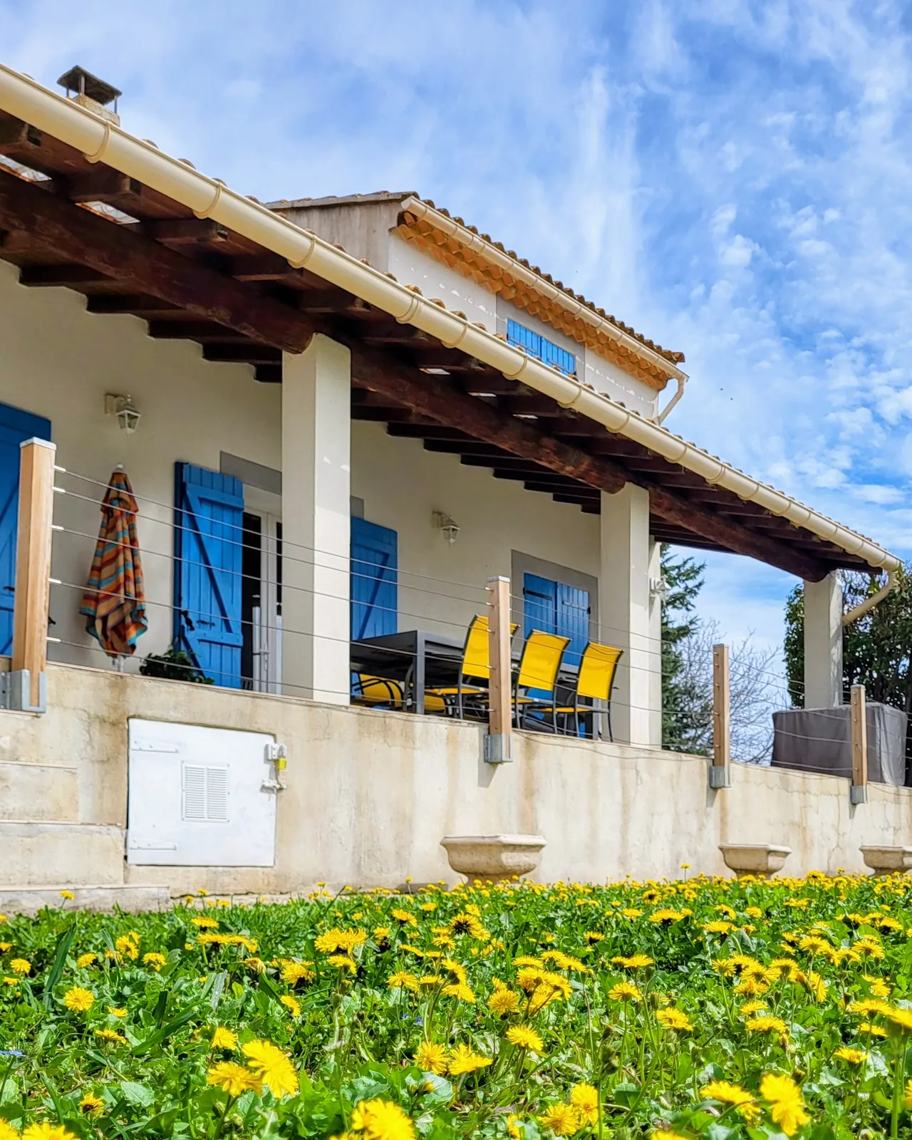 Das Haus mit seiner Terrasse und den blauen Fensterläden, vom Garten aus gesehen