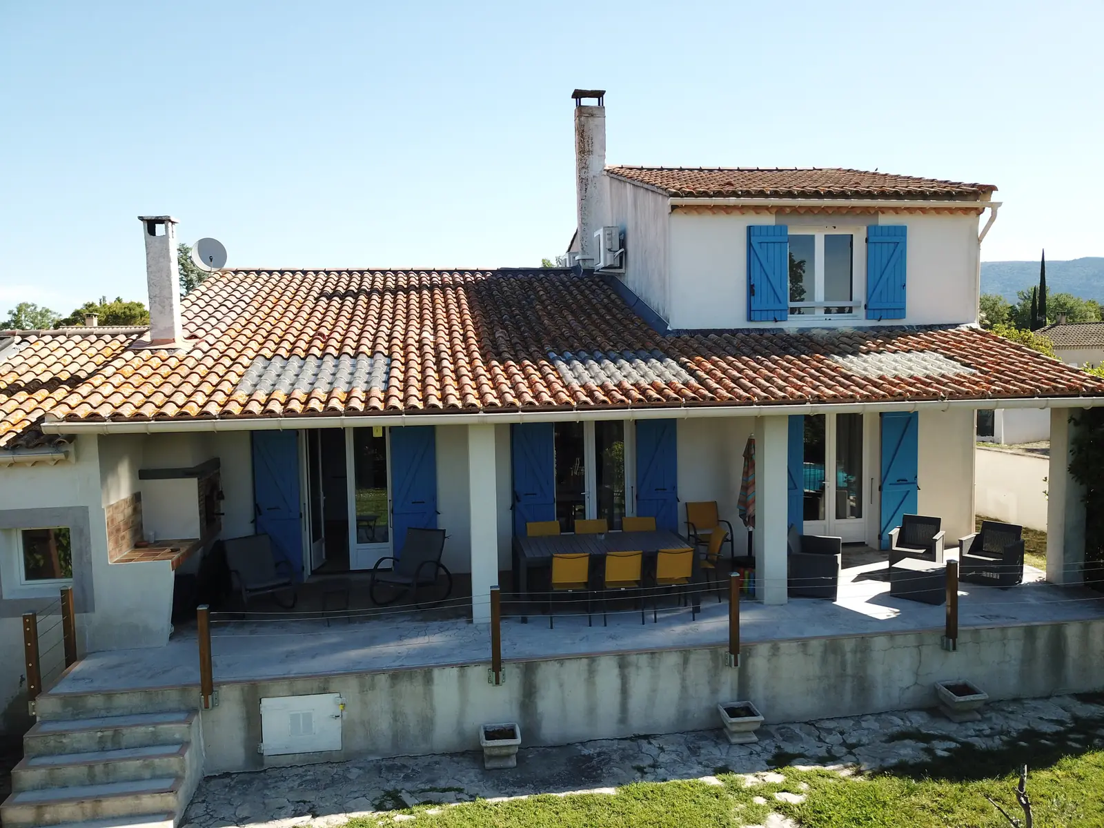 Die überdachte Terrasse mit ihren blauen Fensterläden, Frontansicht