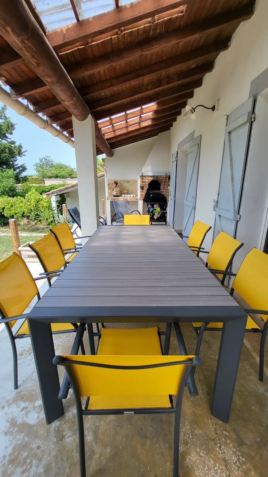 Der grosse Tisch auf der überdachten Terrasse, gedeckt für eine Mahlzeit mit der Familie